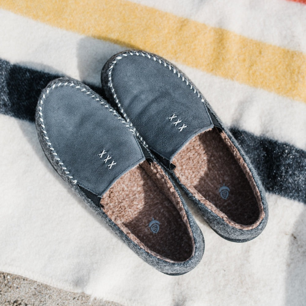 Men's Crafted Moc Slippers flat lay on colorful striped blanket on beach#color_ash